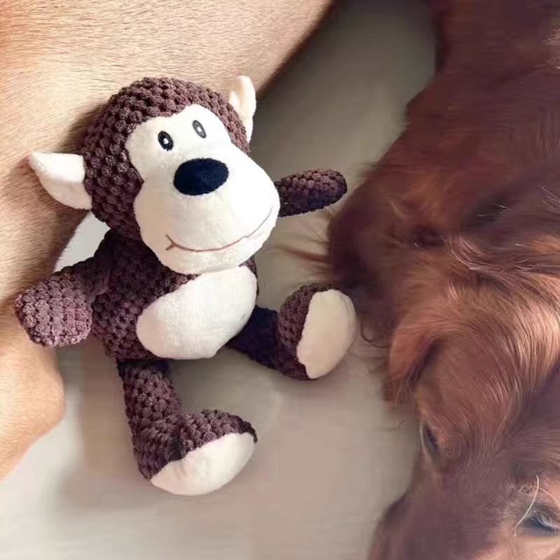 Dog resting beside a brown monkey plush pet toy